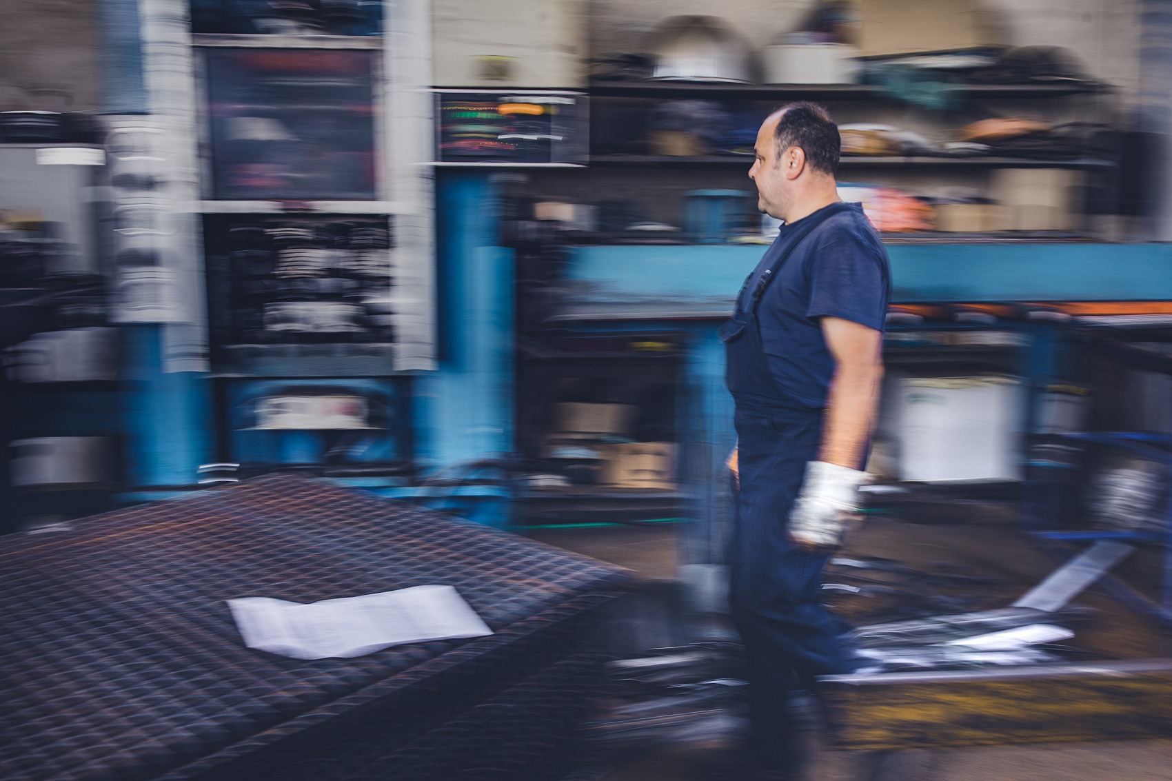 Mid adult metal worker working in aluminum mill. Blurred motion.